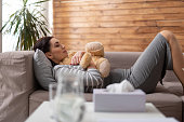 Brunette Caucasian woman lying on sofa with toy in arms