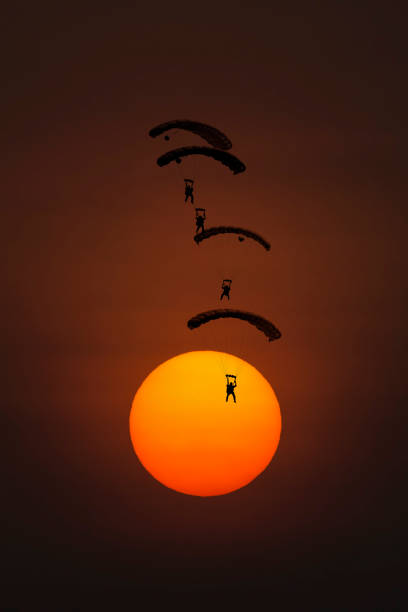 Four silhouette parachutes landing