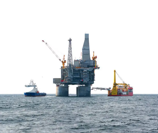 Drilling rig and support vessel on offshore area, sea and white sky background
