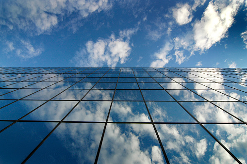 Detail of glass building for business reflection blue sky and clouds