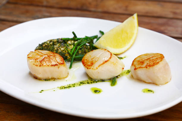 istock Portion of grilled scallops on plate on table 1135124143