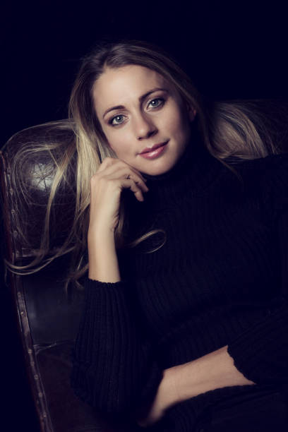 istock Beautiful woman in low light sitting on a brown leather sofa artistic conversion 1135126500