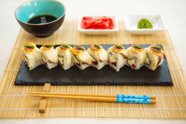istock Variation of sushi and rolls on stone table. Sashimi set. Top view with a copy space. Fried hot Roll with salmon, avocado, cucumber. 1135127443