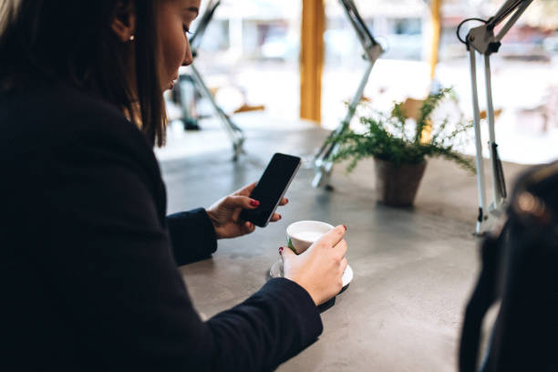 istock Young woman surfing smartphone and drinking coffee 1135132197