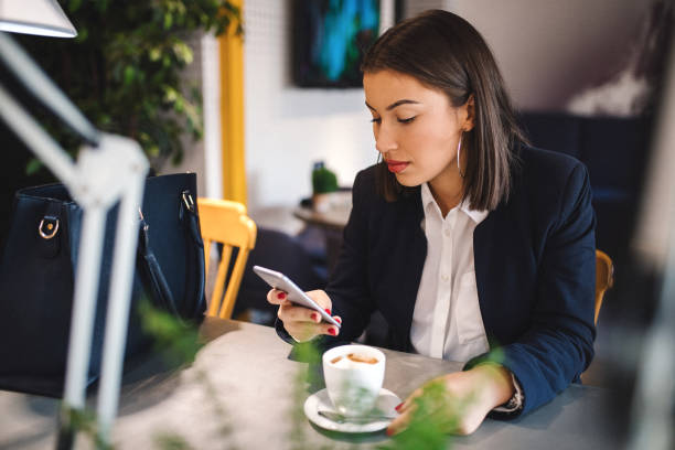 istock Young woman surfing smartphone and drinking coffee 1135133350