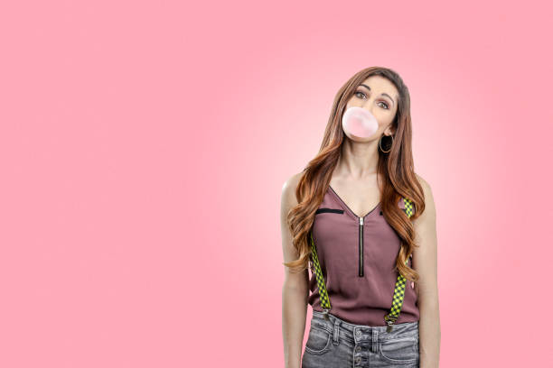 istock Woman blowing pink bubble gum 1135133373