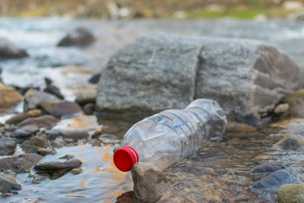 istock Irresponsible people trowing trash in river. Plastic bottle floating in the river 1135138159