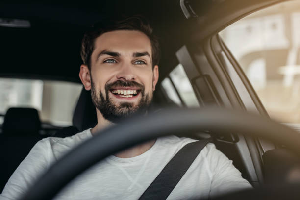 Man in car dealership Young man is choosing a new vehicle in car dealership. motor living stock pictures, royalty-free photos & images