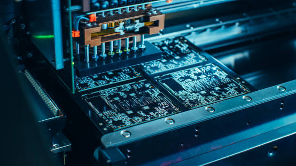istock Factory Machine at Work: Printed Circuit Board Being Assembled with Automated Robotic Arm, Surface Mounted Technology Connecting Microchips to the Motherboard. Macro Close-up . 1135140304