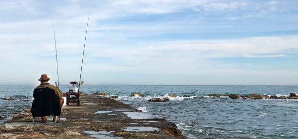 istock Fisherman sitting near the sea 1135140339