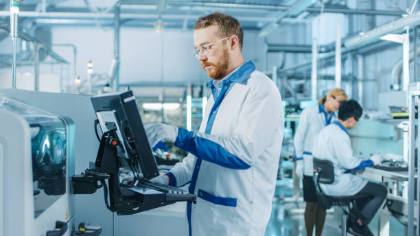 istock On High-Tech Factory Male Engineer Uses Computer for Programing Pick and Place Electronic Machinery for Printed Circuit Board Surface Mount Assembly Line. Production of PCB with SMT Machinery. 1135140470