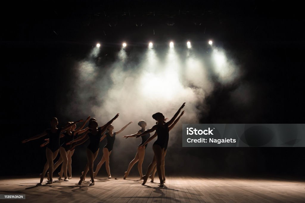 Ballet class on the stage of the theater with light and smoke. Children are engaged in classical exercise on stage. Dancing Stock Photo