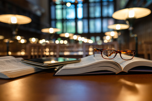 istock Digital Tablet and Eyeglasses On Books in Public Library 1135144614