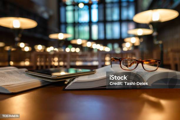 Digital Tablet And Eyeglasses On Books In Public Library Stock Photo - Download Image Now