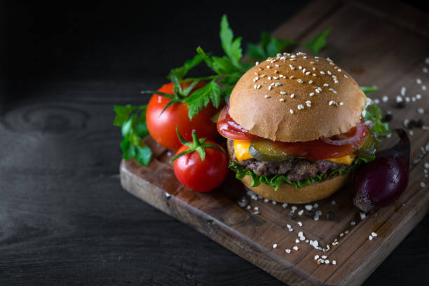 istock Classic american cheeseburger on a wooden board with tomatoes and onion. 1135145567