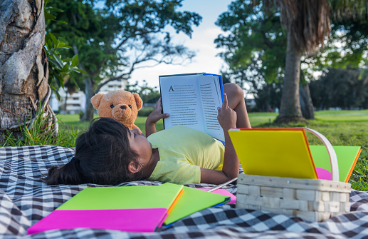Cute girl reading a book to his teddy bear.