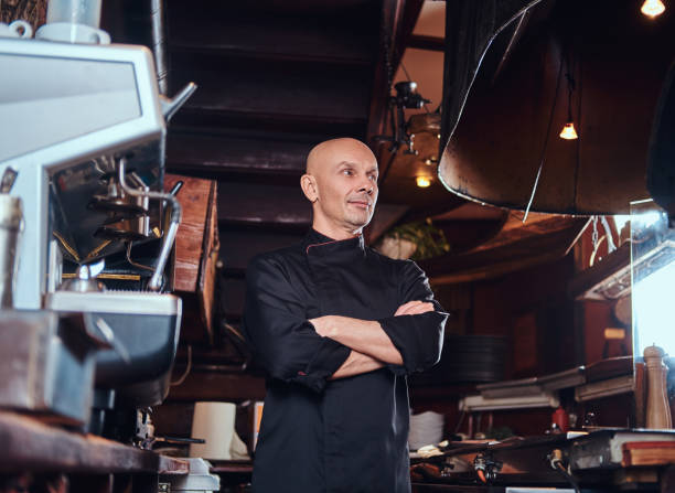 istock Confident chef posing with his arms crossed and looking away in a restaurant kitchen. 1135148307