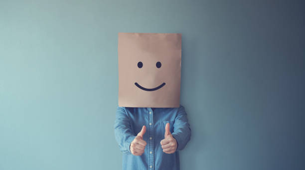 istock Woman covering her face with a smiling face emoticon, copy space. 1135148440