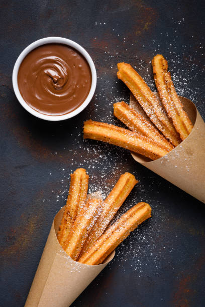 palos de churro tradicionales fritos con azúcar en polvo - churro chocolate cup sweet food fotografías e imágenes de stock