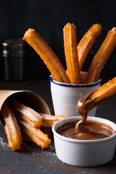 Churro stick in melted flowing chocolate