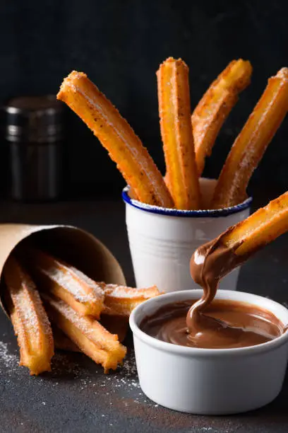 Churro stick in melted flowing chocolate sauce dip