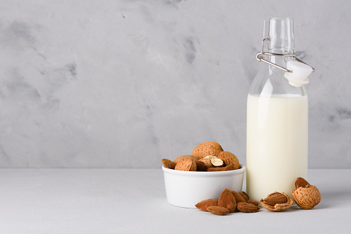 Almond milk with organic almonds nuts on concrete table with copy space