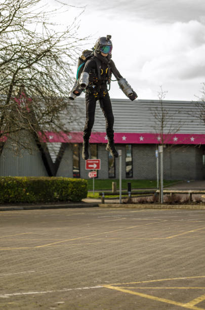 Jet Pack Pilot Ryan Hopgood in Basingstoke BASINGSTOKE, UK - MARCH 11, 2019: Gymnast Ryan Hopgood demonstrating a Gravity Industries jet pack by flying over the car park at Basingstoke Leisure Park. wow airlines stock pictures, royalty-free photos & images