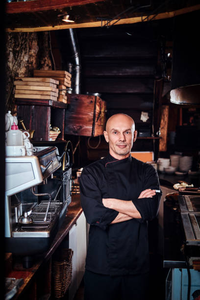 istock Confident chef posing with his arms crossed and looking at a camera in restaurant kitchen. 1135152363