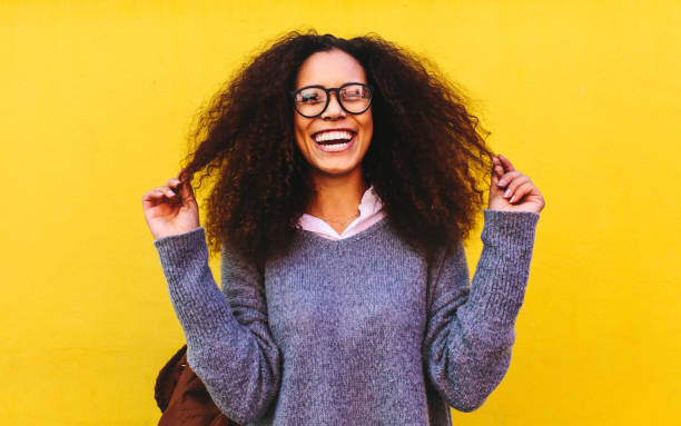 istock Laughing curly haired woman on yellow background 1135152848