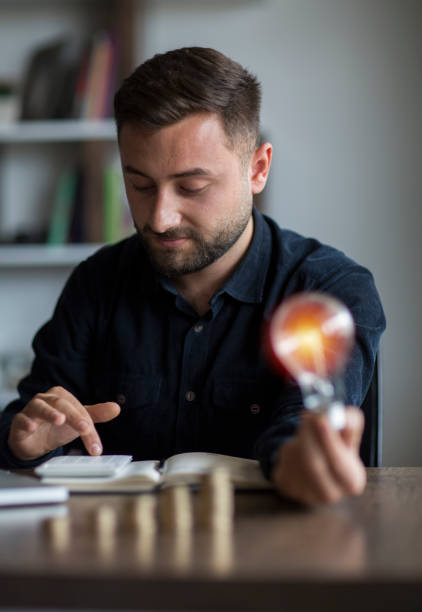 전구 개념 재무 배경을 들고 손으로 돈을 절약 하는 비즈니스 계정 - light bulb led evolution development 뉴스 사진 이미지