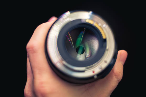 istock DSLR lens in hand with partly closed aperure, visible aperture blades. 1135156503