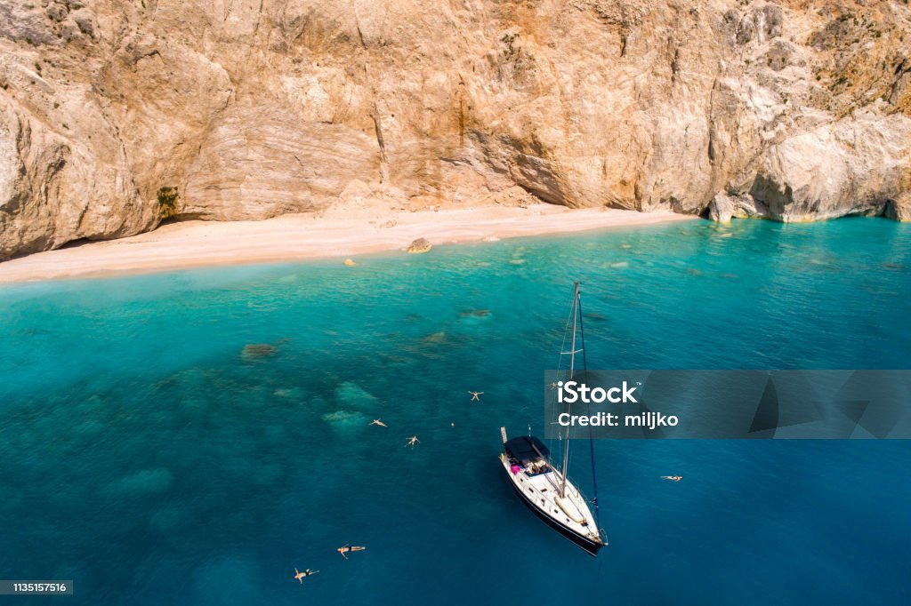 Discover Greece - Lefkada island Sailboat anchored in bay of Porto Katsiki beach. This beach is famous mostly because of crystal clear water and because of their amazing color. Lefkada Island Stock Photo