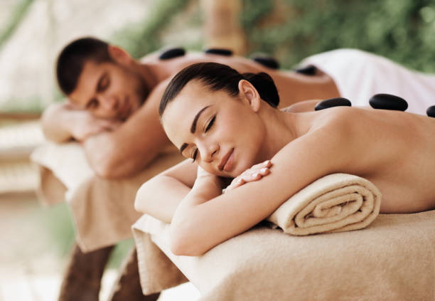 couples ayant la thérapie de pierre chaude extérieure - health spa couple spa treatment towel photos et images de collection