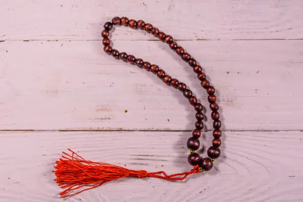 Photo of Brown rosary on the white wooden table. Top view