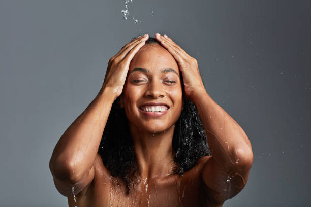 Time to freshen up Studio shot of an attractive young woman posing against a grey background wet hair stock pictures, royalty-free photos & images