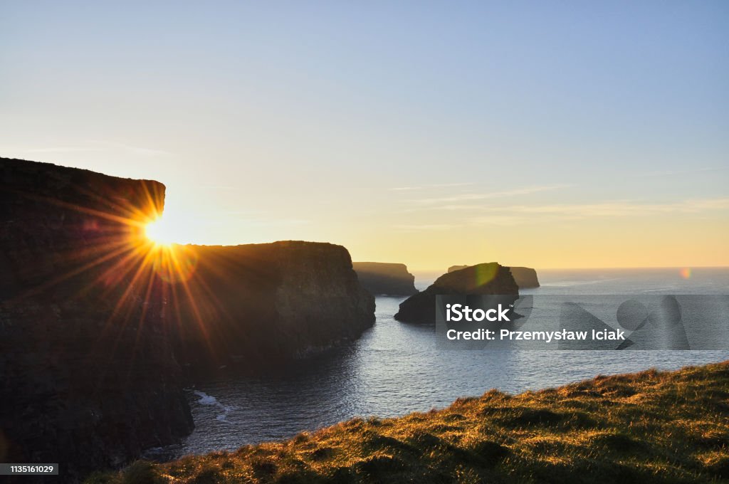 Sunny Cliffs of Kilkee in Ireland county Clare Sunset. Tourist destination The Kilkee Cliff walk is a scenic 2 to 3 hour (8km) moderate loop walk along the Kilkee Cliffs starting at the Diamond Rocks Café, Pollock Holes car park. Beach Stock Photo