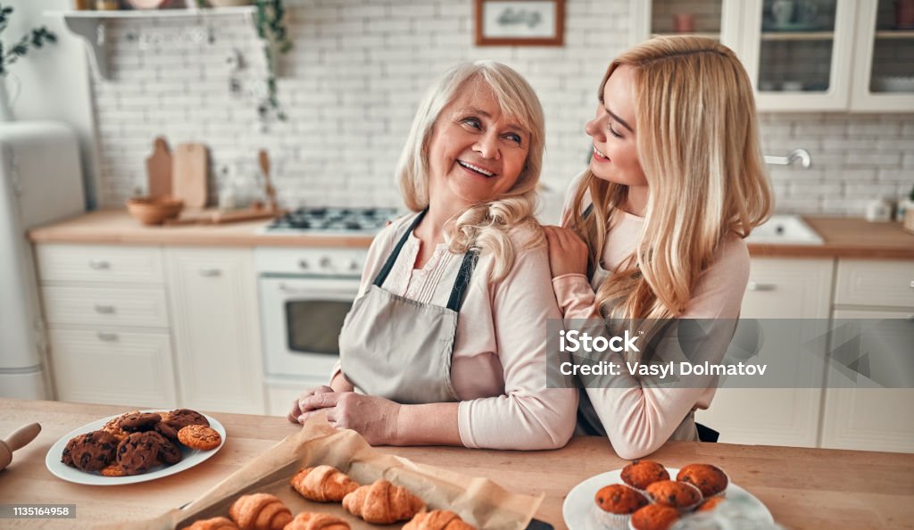 Mother with daughter at home Senior woman and her attractive daughter spending time together at home. Cooking together on kitchen. Happy Mothers' Day. Mother Stock Photo