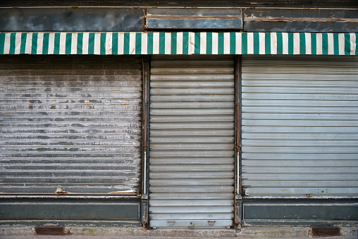 Ancient storefront with metallic closed curtains. Abandoned shop business.