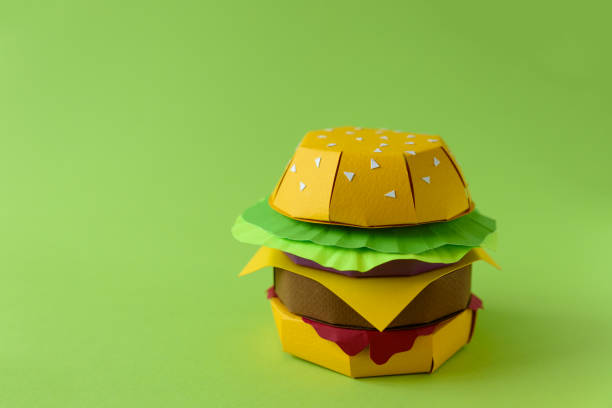 istock Paper burger with beef, cheese, lettuce and onions on a green background. Copy space. Creative or art food concept 1135166257