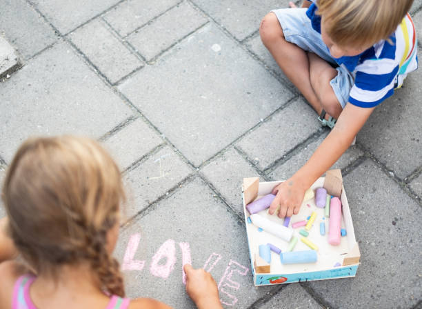 istock High angle view boy and girl writing with chalk on concrete 1135171970