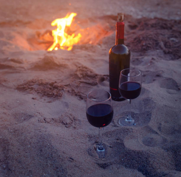 istock Two wineglasses on beach near campfire. 1135173620