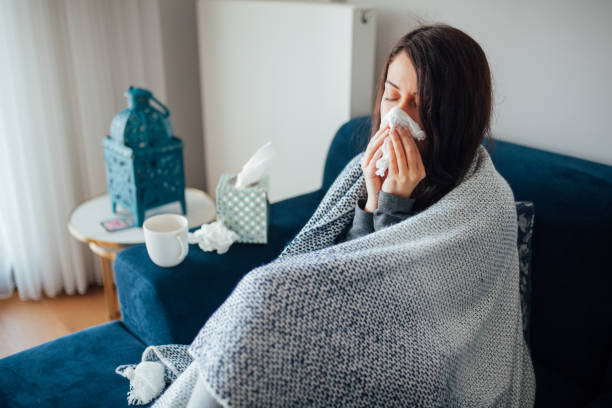 istock Sick woman blowing her nose, she covered with blanket 1135175102