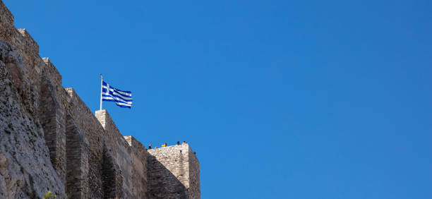 atene, grecia, roccia dell'acropoli, bandiera greca che sventola su cielo blu chiaro, striscione - clear sky acropolis athens greece greece foto e immagini stock