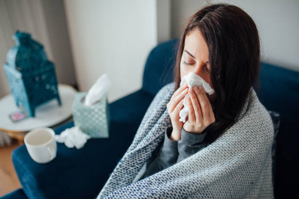 istock Sick woman blowing her nose, she covered with blanket 1135175291