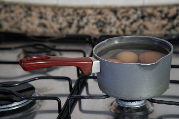 Boiled eggs in dipper of water on the kitchen stove