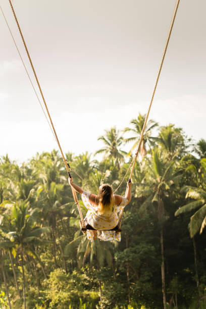 Woman swinging in the jungle, Bali Younfg woman on famous Bali swings over rice fields in Ubud and Tegallalang, Indonesia during sunrise ubud photos stock pictures, royalty-free photos & images