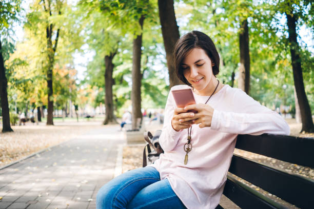 istock Young woman using phone in public park 1135179224