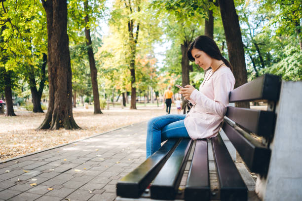 istock Young woman using phone in public park 1135179308
