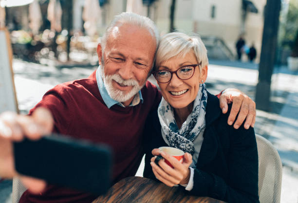 Mature couple taking selfie Mature couple taking selfie in sidewalk cafe short silver hair stock pictures, royalty-free photos & images