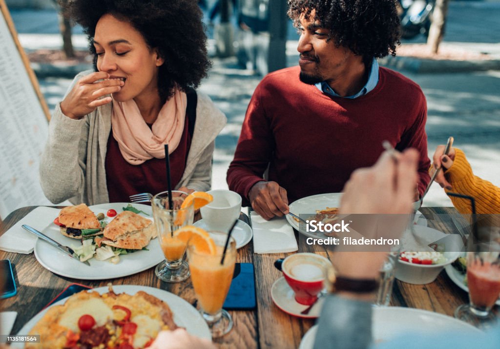 Enjoying the meal outdoor Afro-american couple enjoying healthy lunch with friends in restaurant outdoor Brunch Stock Photo